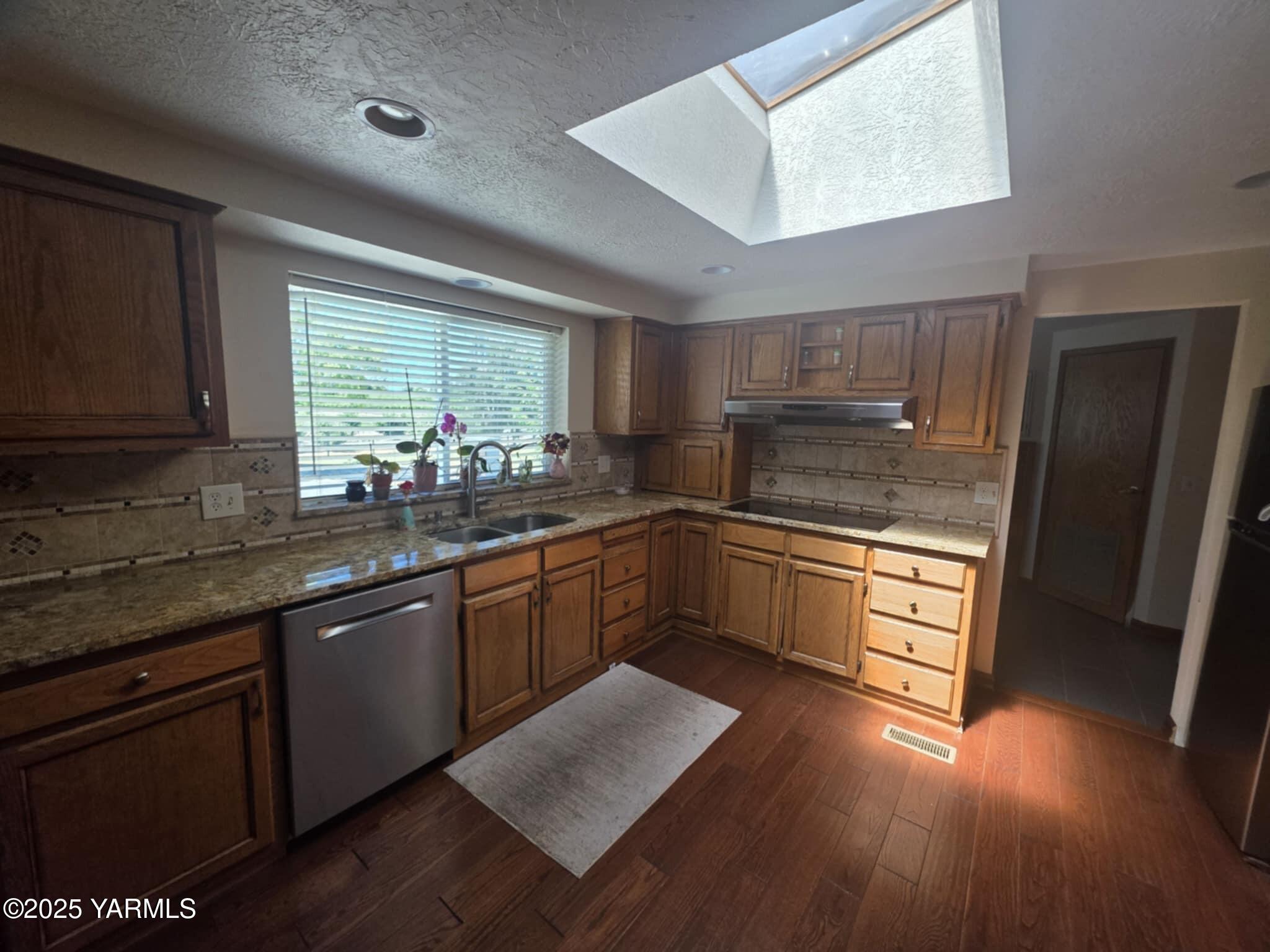 5202 Norman Road Yakima, WA 98901 - Photo 24 of 48 a kitchen with stainless steel appliances kitchen island granite countertop wooden cabinets a sink and dishwasher a stove with wooden floor