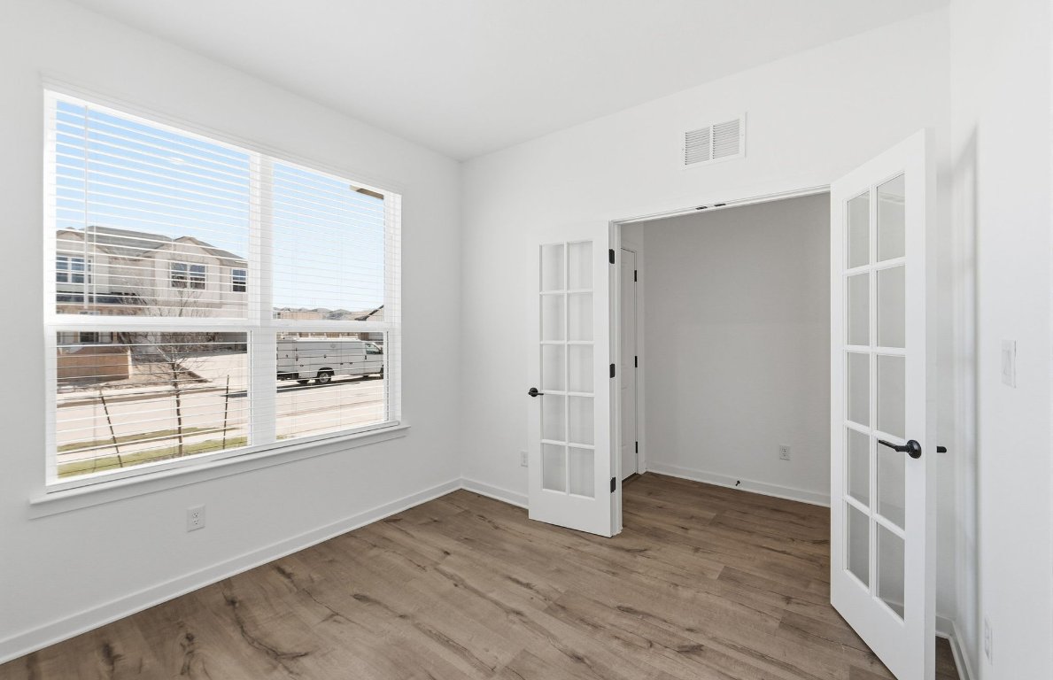 290 Begonia Street Buda, TX 78610 - Photo 12 of 25 a view of an empty room with wooden floor and a window