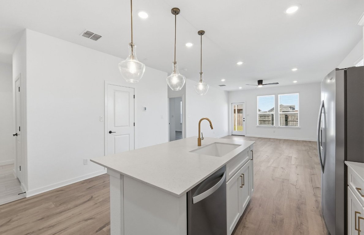 290 Begonia Street Buda, TX 78610 - Photo 6 of 25 a kitchen with a sink a stove a refrigerator and wooden floor