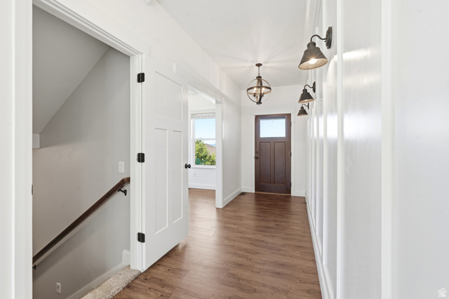 338 Windy Rdg Drive Smithfield, UT 84335 - Photo 7 of 63 Entryway featuring wood-finish flooring, a dark wood front door with glass panel, white paneled walls, and a contemporary chandelier
