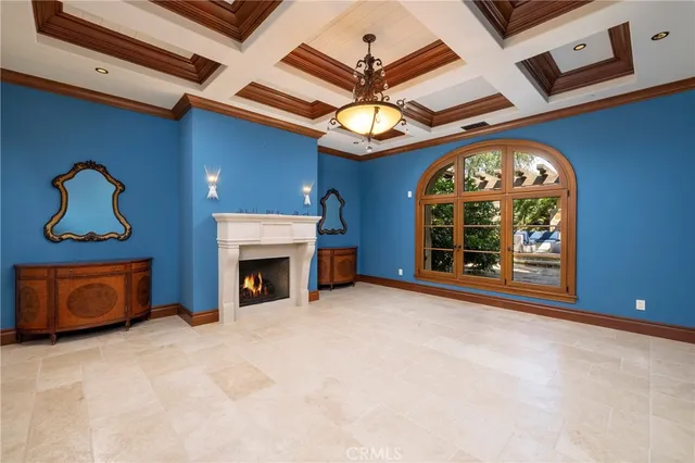 a view of a livingroom with a fireplace a chandelier and windows