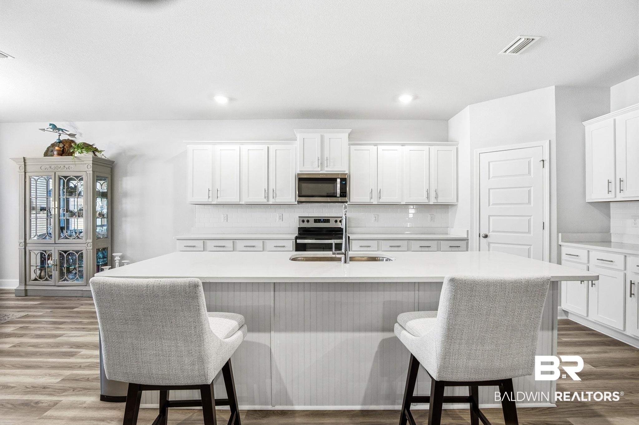 11123 Genuine Risk Circle Daphne, AL 36526 - Photo 16 of 67 Kitchen with decorative backsplash, white cabinets, dark wood finished floors, a kitchen breakfast bar, and recessed lighting