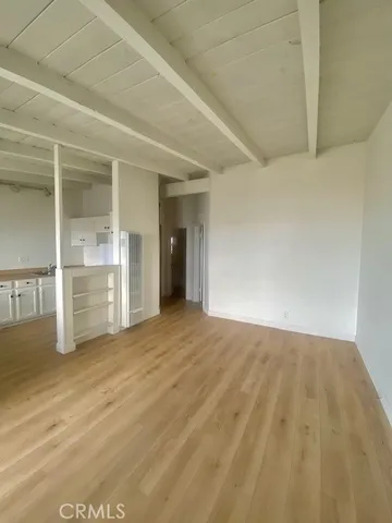 a view of an empty room with kitchen and a window