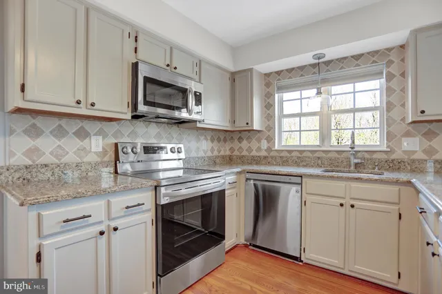 a kitchen with granite countertop white cabinets stainless steel appliances and a sink