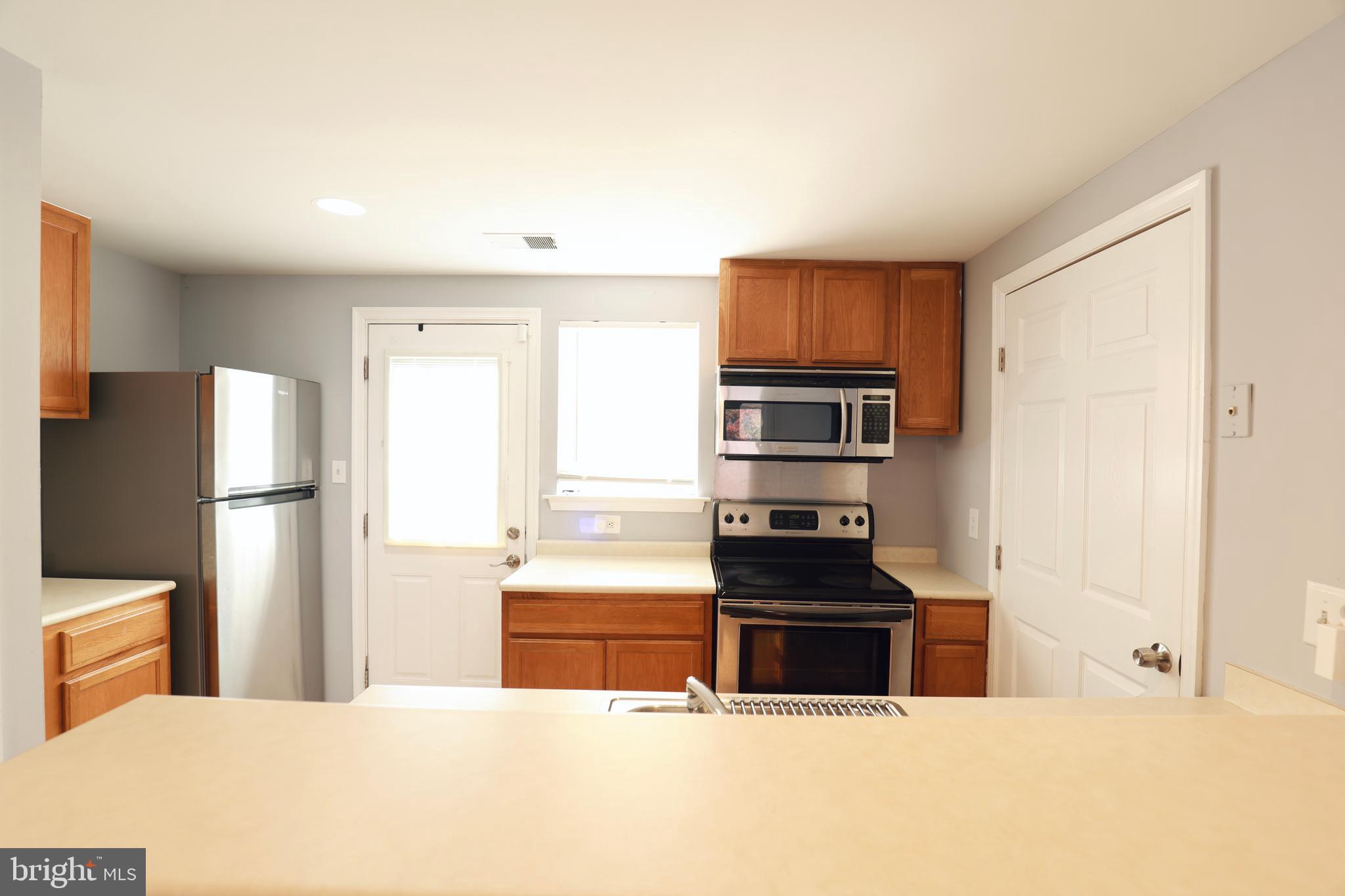 4393 Pembrook Village Drive, Unit 84 Alexandria, VA 22309 - Photo 12 of 38 a kitchen with granite countertop a refrigerator and a stove top oven