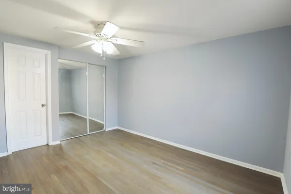 an empty room with wooden floor and fan