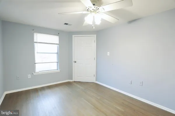 an empty room with wooden floor chandelier fan and windows