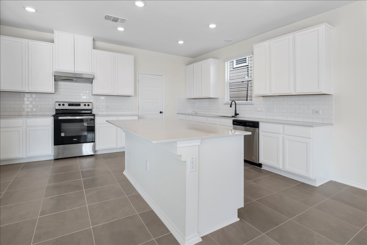 18501 Spotted Eagle Lane Elgin, TX 78621 - Photo 7 of 40 A well-lit kitchen with sleek white cabinetry, gleaming countertops, and durable tile flooring.