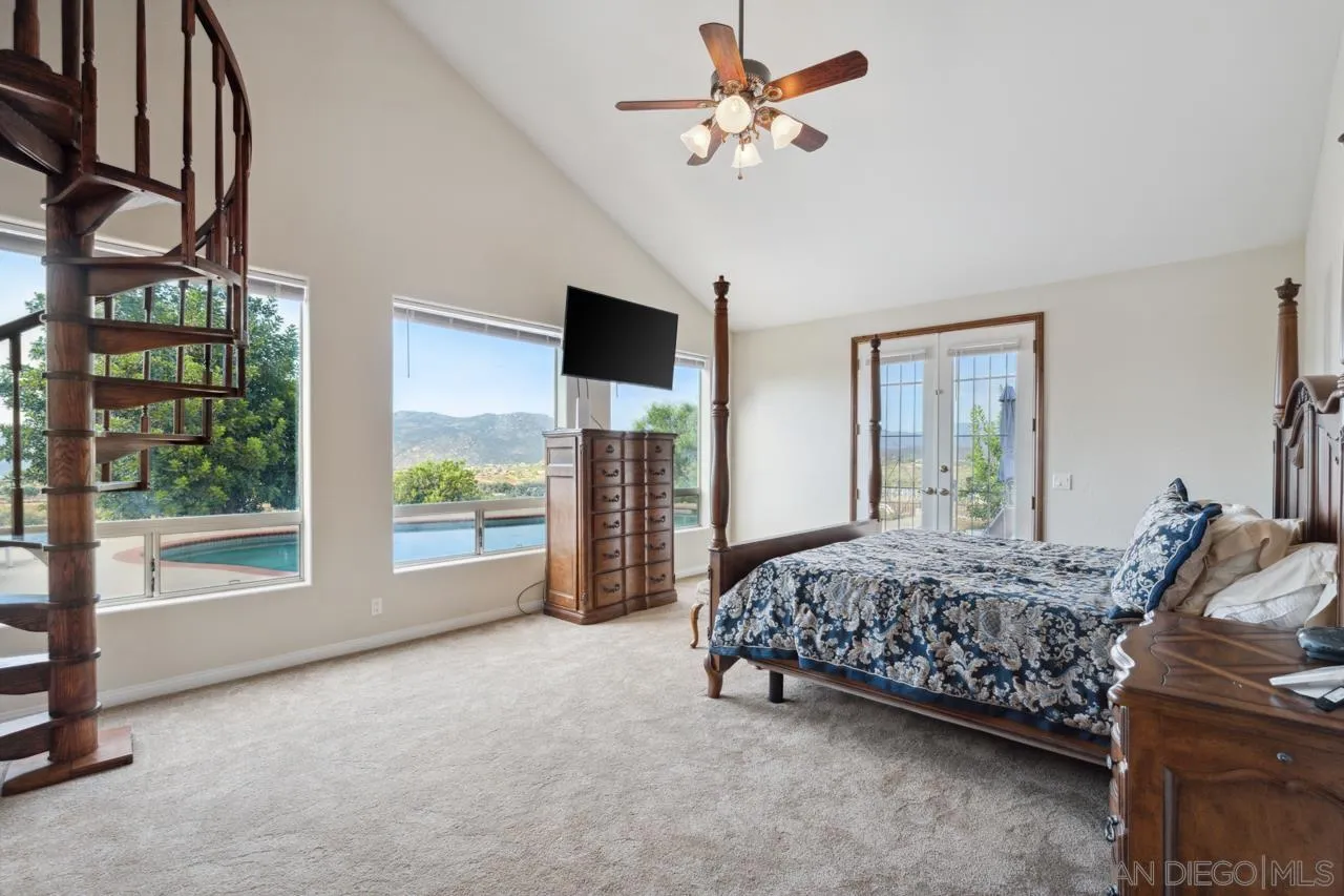 15091 Chemise Creek Road Ramona, CA 92065 - Photo 52 of 74 a spacious bedroom with a large bed and a chandelier
