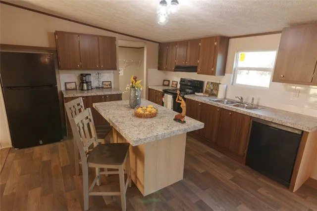 a kitchen with granite countertop stainless steel appliances a sink a stove a refrigerator cabinets and a dining table