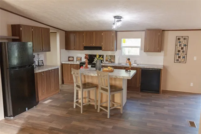 a kitchen with stainless steel appliances granite countertop a stove a refrigerator a sink a dining table and chairs