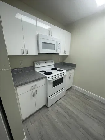 a kitchen with granite countertop white cabinets and white appliances