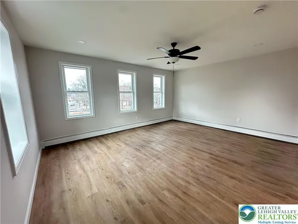 a view of an empty room with a window and wooden floor