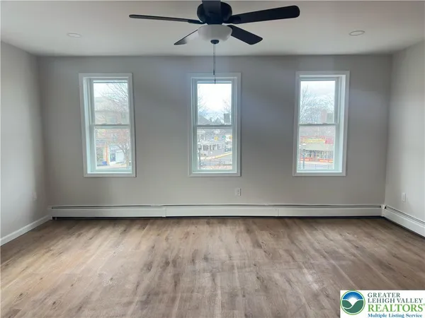 a view of an empty room with wooden floor and a window