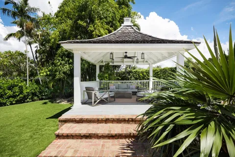a view of a patio with a table and chairs under an umbrella with a garden