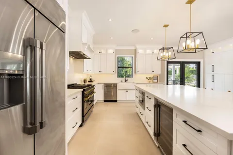 a large kitchen with stainless steel appliances kitchen island granite countertop a refrigerator a sink dishwasher a oven with white cabinets and wooden floor