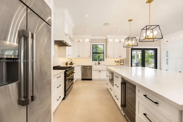 a large kitchen with stainless steel appliances kitchen island granite countertop a refrigerator a sink dishwasher a oven with white cabinets and wooden floor