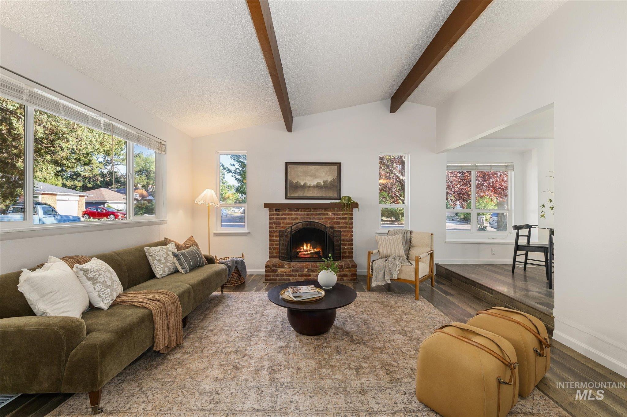 2302 Pendleton Street Boise, ID 83705 - Photo 5 of 35 Vaulted ceiling with exposed wood beams, brick fireplace, wood-finish flooring, and multiple windows