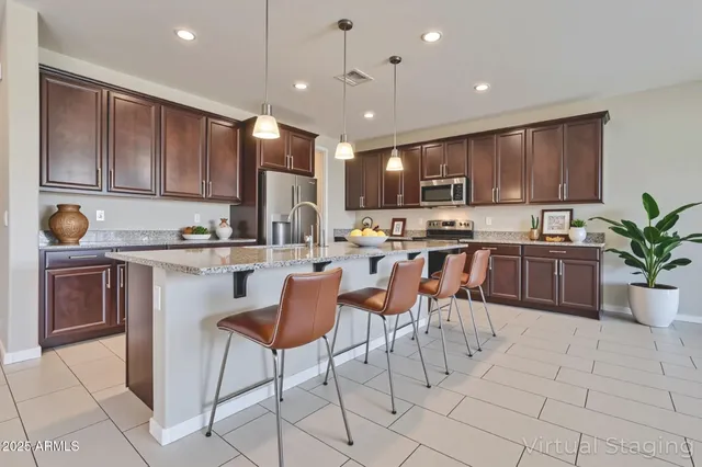 a kitchen with stainless steel appliances kitchen island granite countertop a sink a stove a dining table and chairs