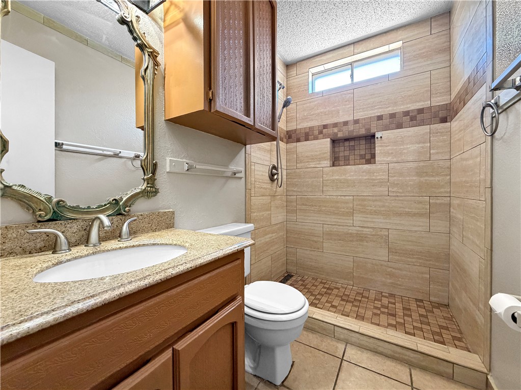 910 Twite Circle Corpus Christi, TX 78418 - Photo 27 of 40 a bathroom with a granite countertop sink toilet a mirror and shower