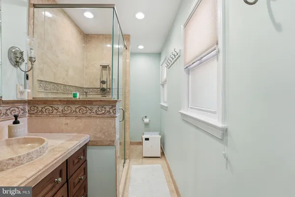 a bathroom with a granite countertop sink a mirror and a shower