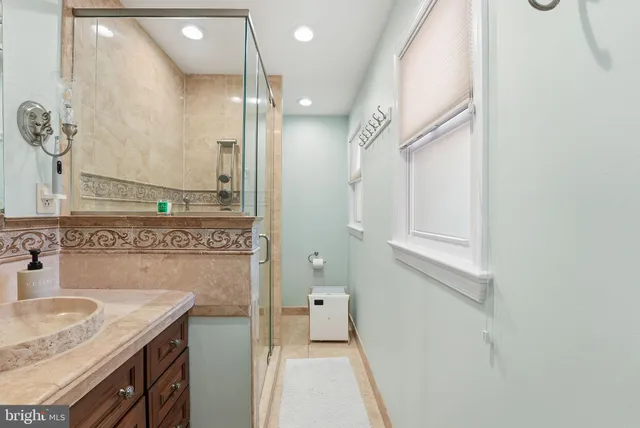 a bathroom with a granite countertop sink a mirror and a shower