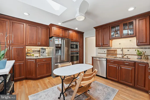 a kitchen with stainless steel appliances granite countertop wooden cabinets a dining table and chairs