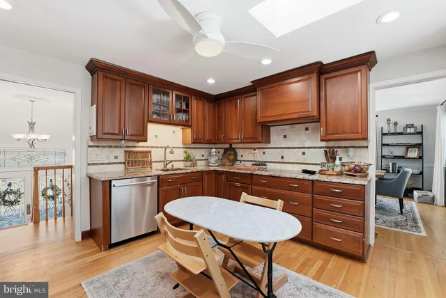 a kitchen with granite countertop wooden floors cabinets dining table and stainless steel appliances