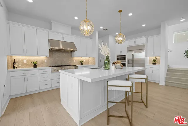 a large white kitchen with lots of counter space dining table and chairs