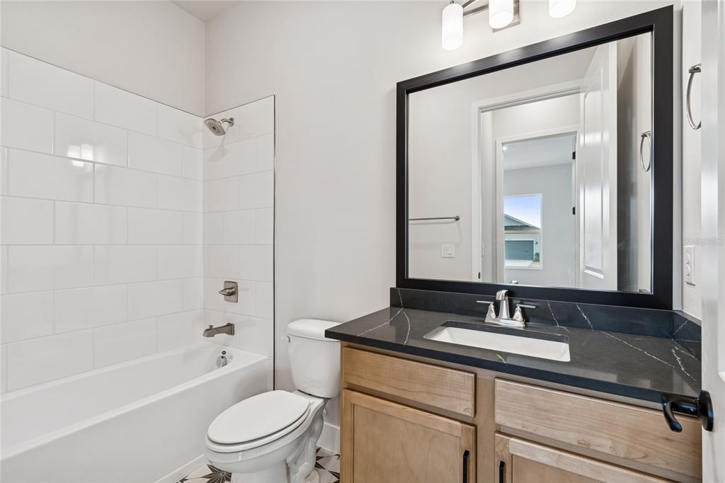 31479 Hayman Loop Wesley Chapel, FL 33545 - Photo 30 of 45 a bathroom with a sink a toilet a mirror a bathtub and shower