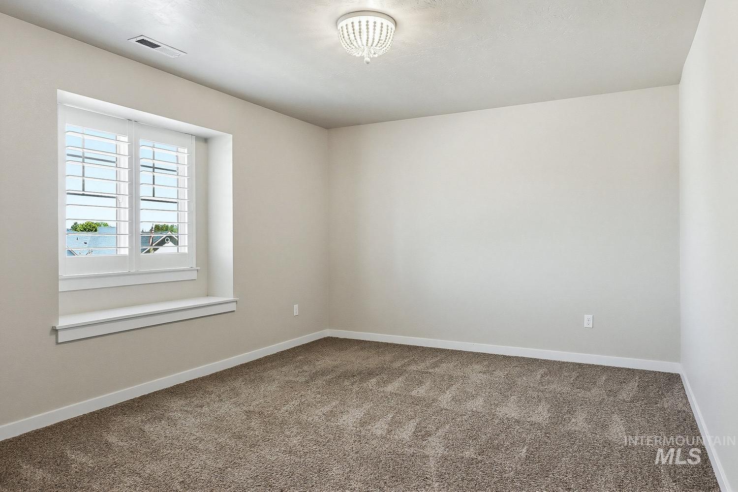 846 North Hidden View Way Star, ID 83669 - Photo 37 of 49 Bright room featuring a window with plantation shutters, a wide window sill, neutral wall tones, and textured carpeting