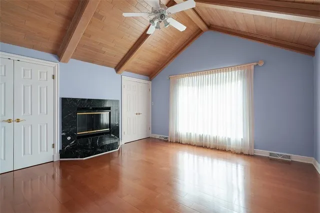 an empty room with wooden floor fireplace and windows