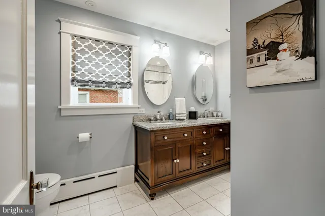 a bathroom with a granite countertop double vanity sink and a mirror