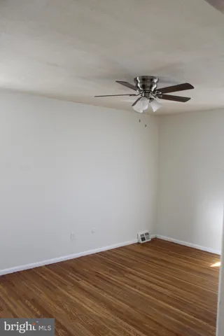 a view of a room with wooden floor and a ceiling fan