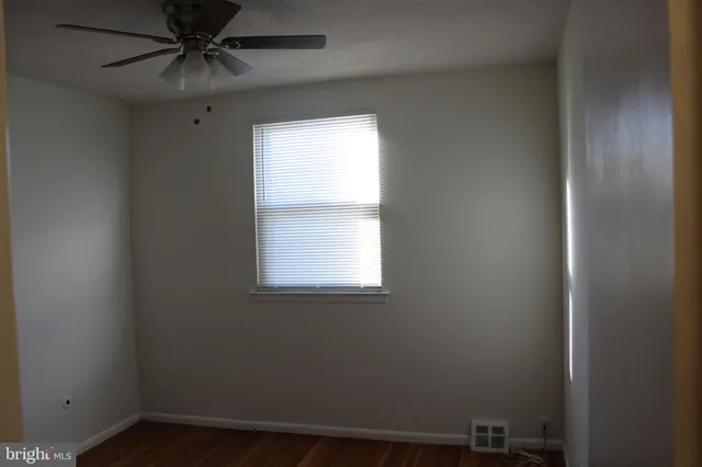 an empty room with a window and a fan
