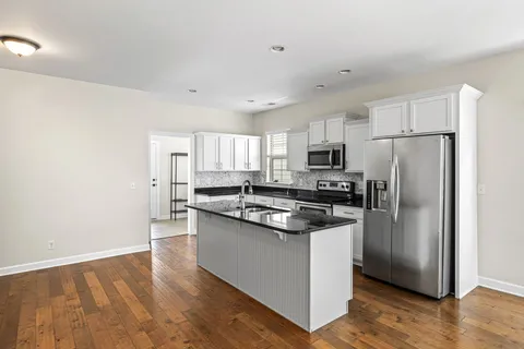 a kitchen with granite countertop a stove top oven a sink a counter space and cabinets