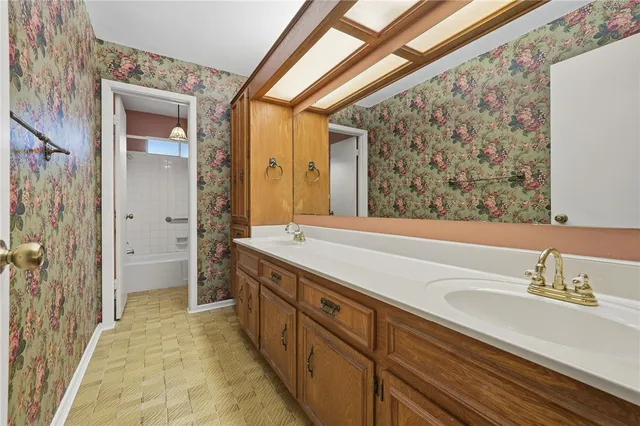 a spacious bathroom with a double vanity sink a mirror and a shower