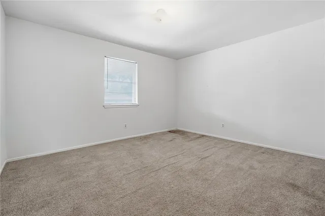 an empty room with windows and chandelier fan