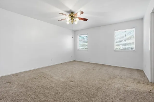 an empty room with a ceiling fan and window