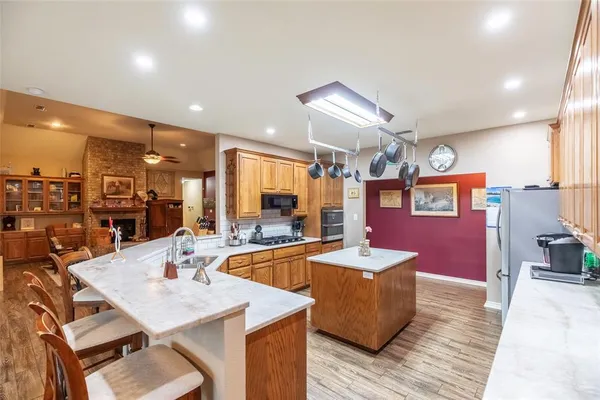 a dining hall with stainless steel appliances kitchen island granite countertop a sink table and chairs