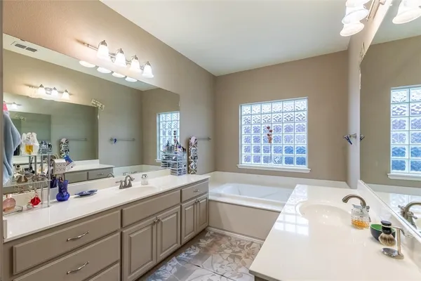 a spacious bathroom with a tub double sink and mirror
