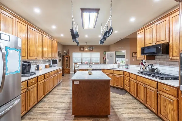 a large kitchen with stainless steel appliances kitchen island granite countertop a sink counter space cabinets and a large window