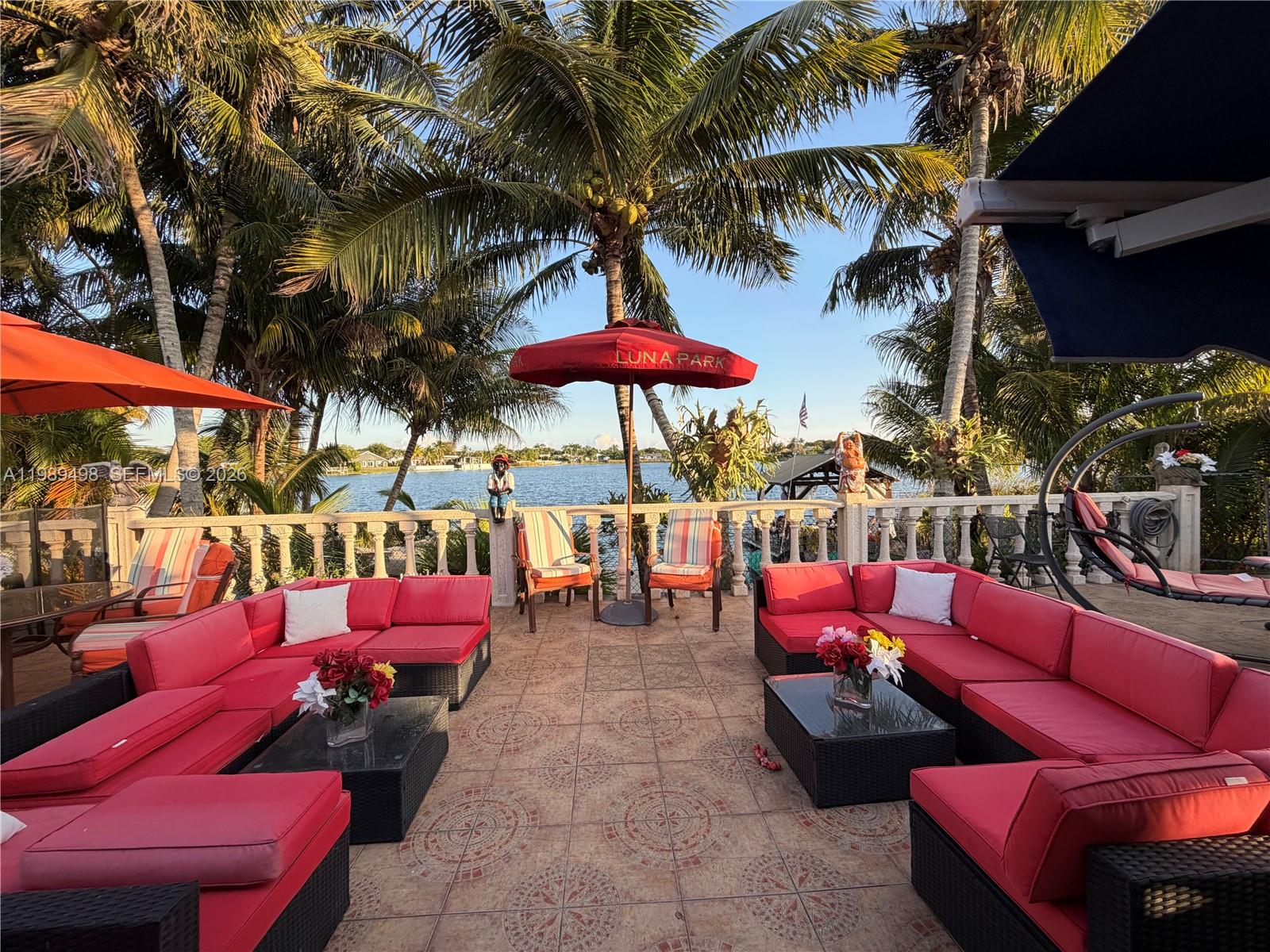 15022 Southwest 67th Lane Miami, FL 33193 - Photo 10 of 15 a view of a patio with a dining table and chairs under an umbrella with a fire pit