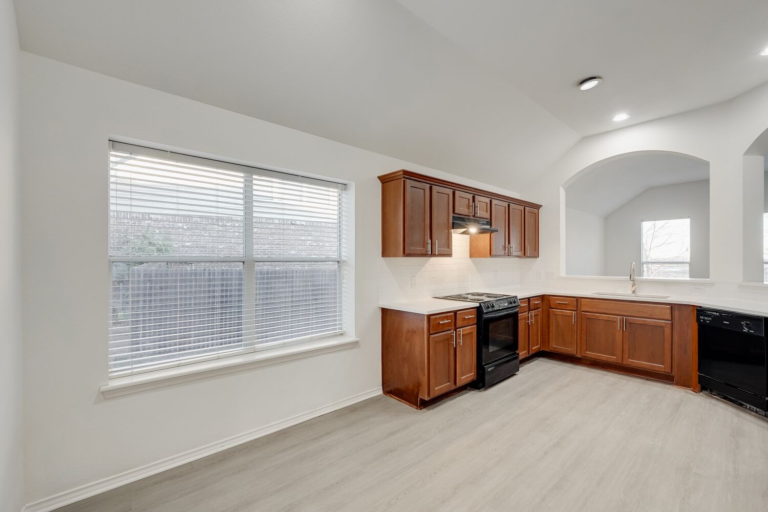 298 Fall Drive Kyle, TX 78640 - Photo 12 of 23 Kitchen with vaulted ceiling, new black appliances, quartz countertops, vinyl plank flooring, and wood cabinets