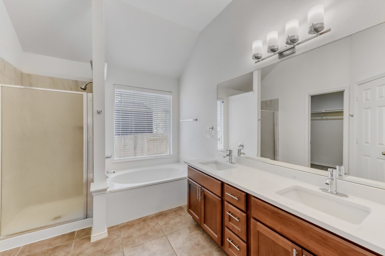 298 Fall Drive Kyle, TX 78640 - Photo 9 of 23 Primary Bathroom with a stall shower, a walk in closet, double vanity, a garden tub, and light tile patterned floors