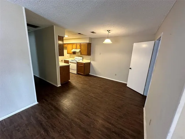 a view of an empty room with wooden floor and a fireplace