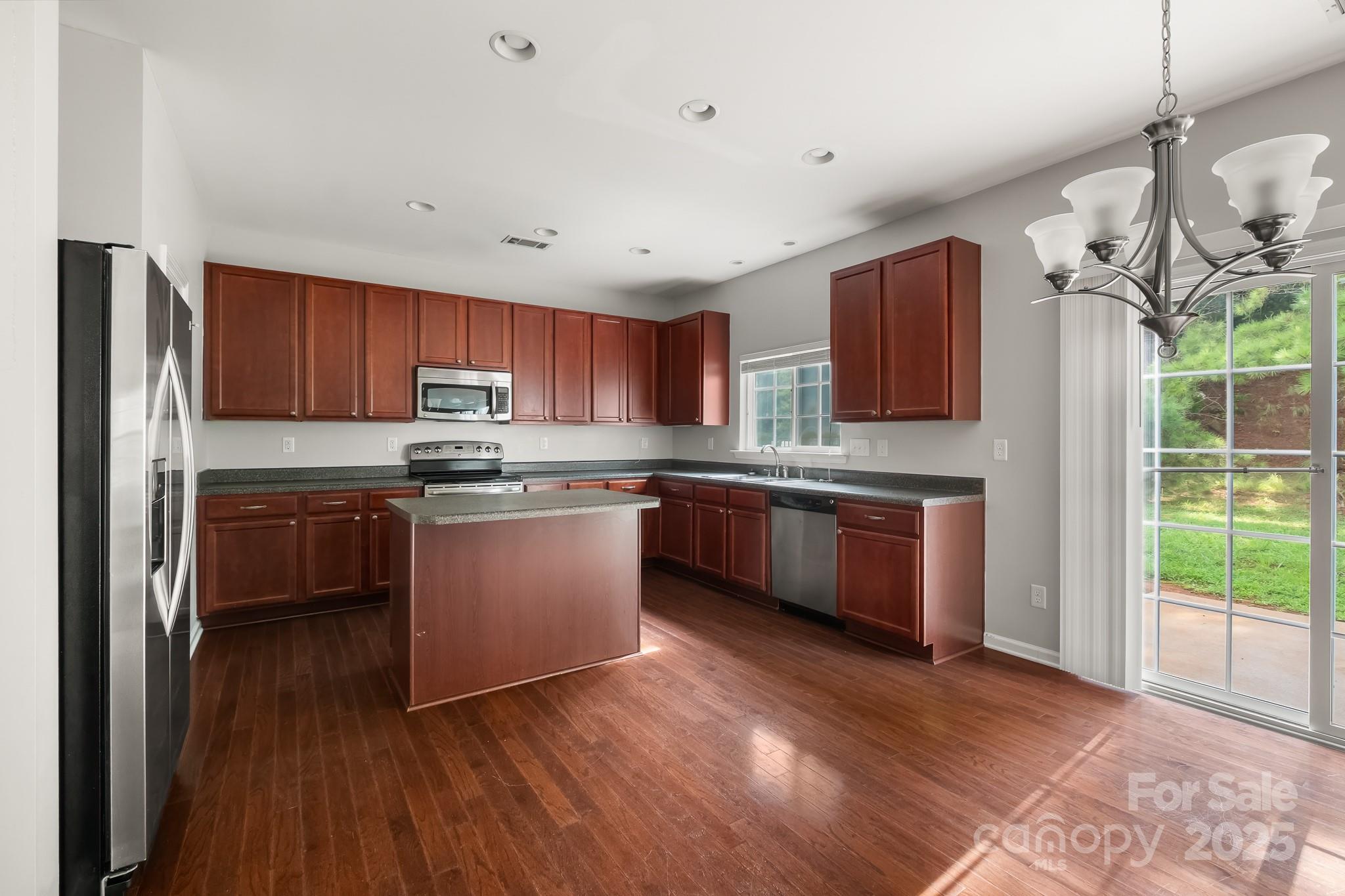 9607 Seamill Road Charlotte, NC 28278 - Photo 4 of 18 a kitchen with stainless steel appliances granite countertop a refrigerator a sink dishwasher a stove top oven a kitchen island with cabinets and wooden floor