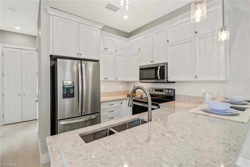 1395 Curlew Avenue, Unit 43 Naples, FL 34102 - Photo 9 of 31 a kitchen with stainless steel appliances granite countertop a refrigerator stove and white cabinets