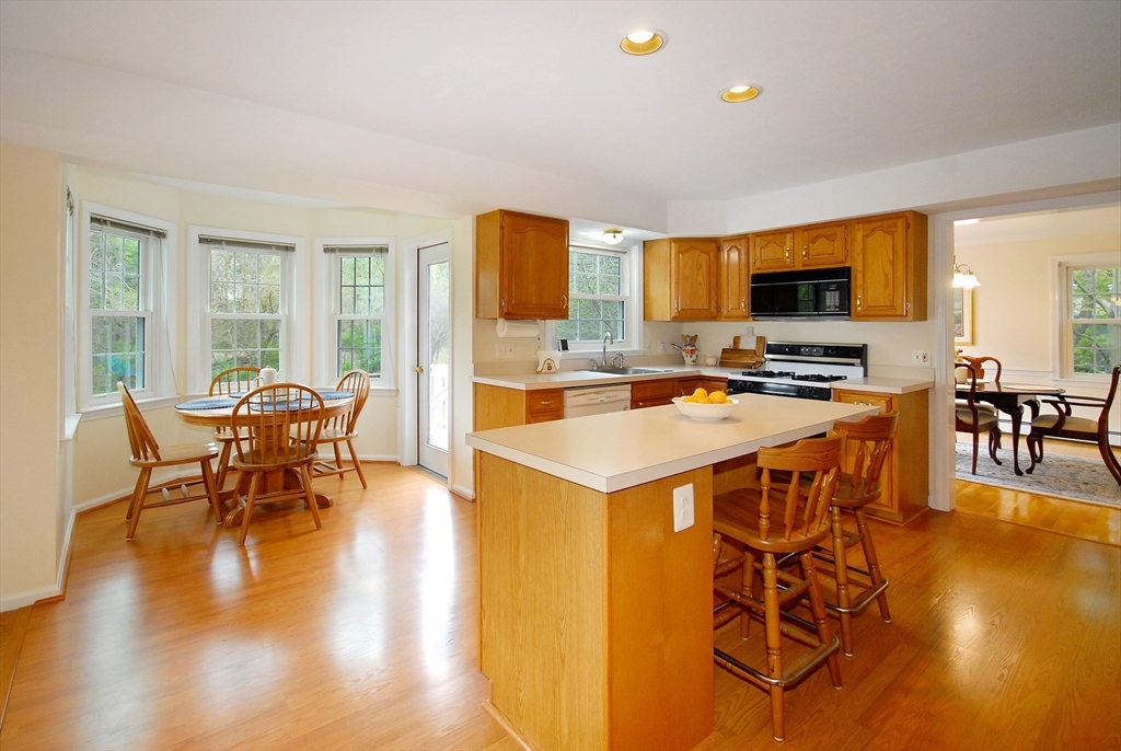 257 North Road Sudbury, MA 01776 - Photo 5 of 30 a kitchen with stainless steel appliances a stove top oven a dining table and chairs with wooden floor