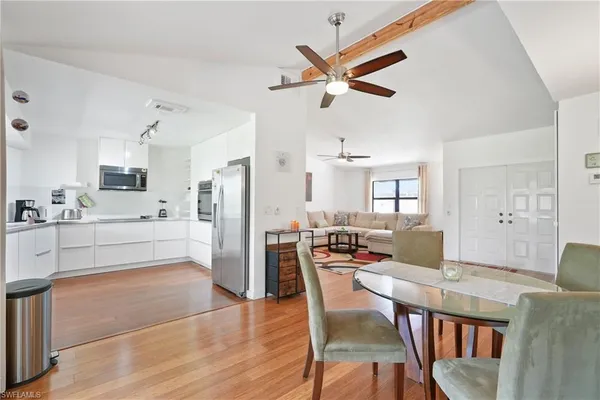 a open kitchen with stainless steel appliances kitchen island granite countertop a dining table chairs and a refrigerator